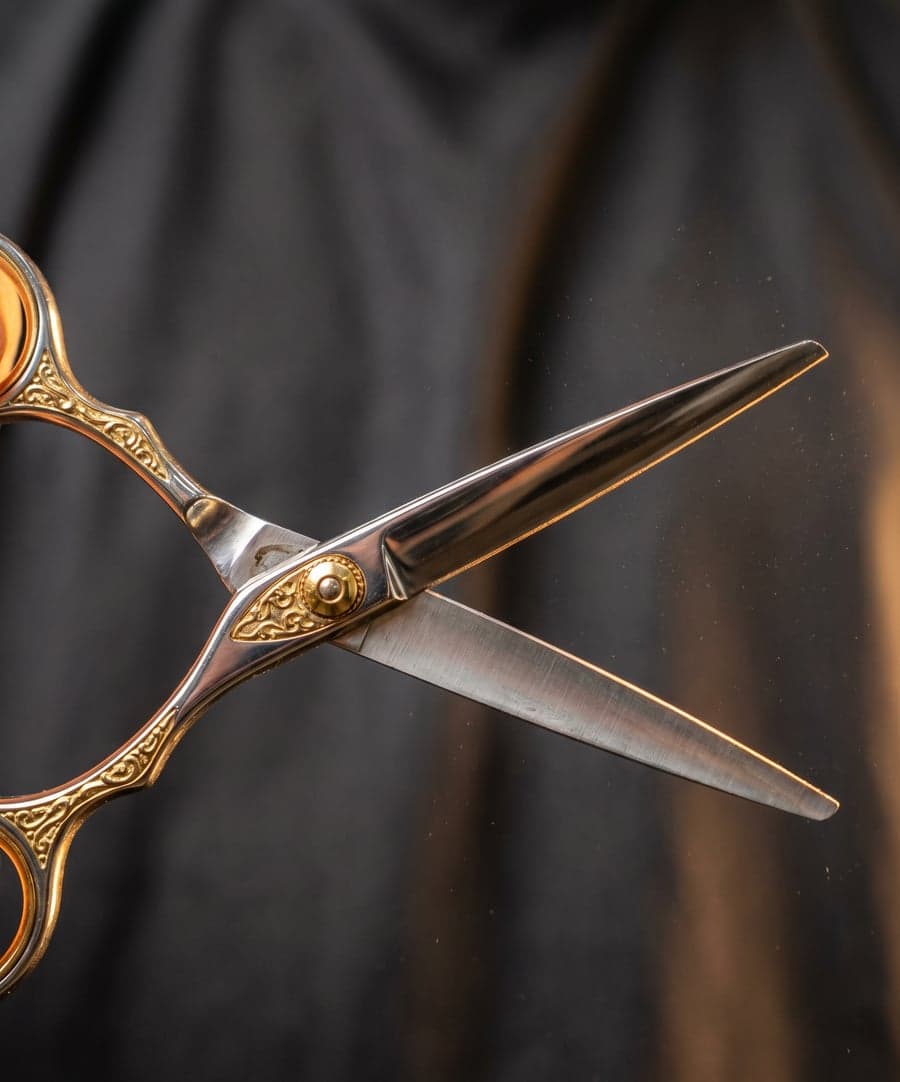 Ornate gold barber scissors open against a dark backdrop
